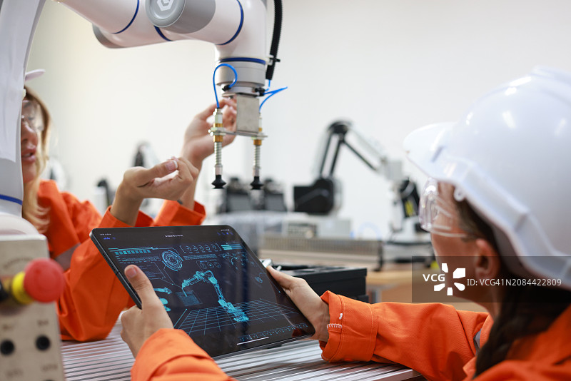 女维修工程师在实验室使用数字平板电脑和机器人手臂分析图表数据图片素材