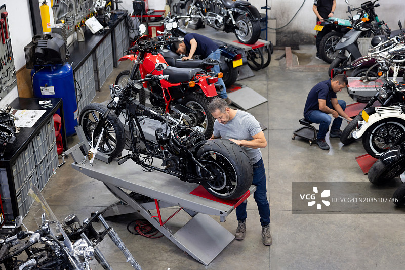 在车库修理摩托车的技工团队图片素材