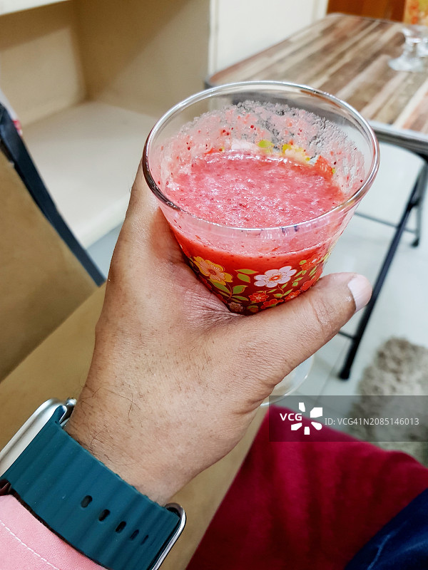 手拿花纹玻璃杯中的红色果汁或冰沙图片素材