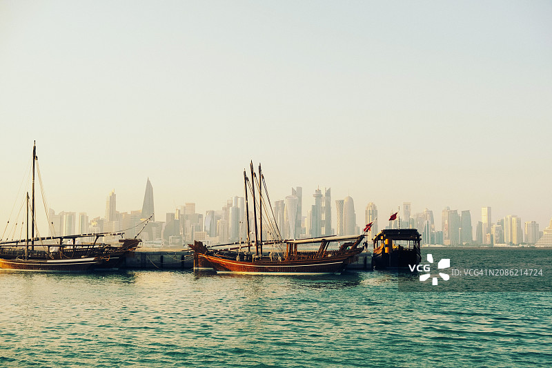 多哈海湾的传统船只与现代城市天际线背景图片素材