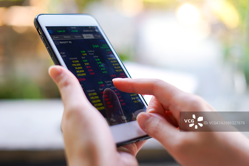 女人使用智能手机查看股市图片素材