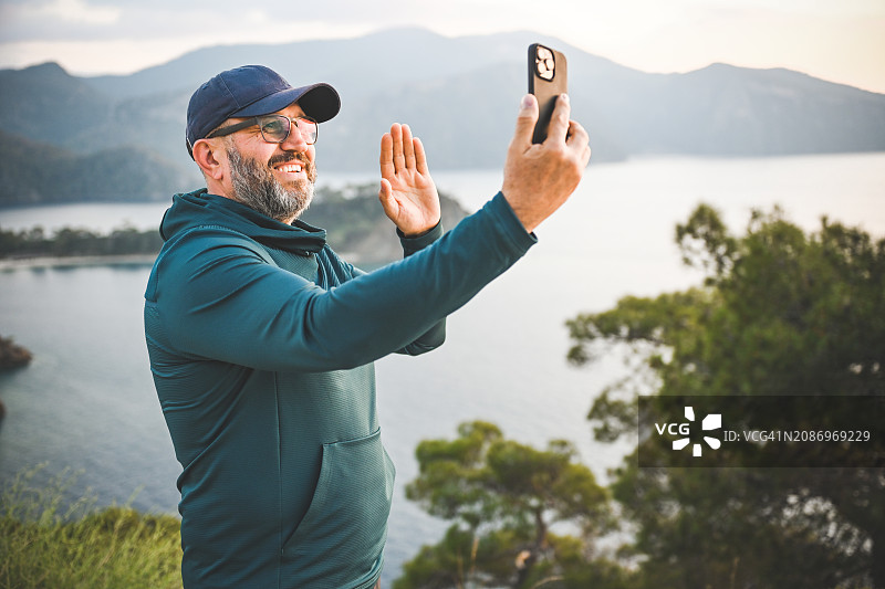 在海洋和山脉背景下，有魅力的中年男人图片素材