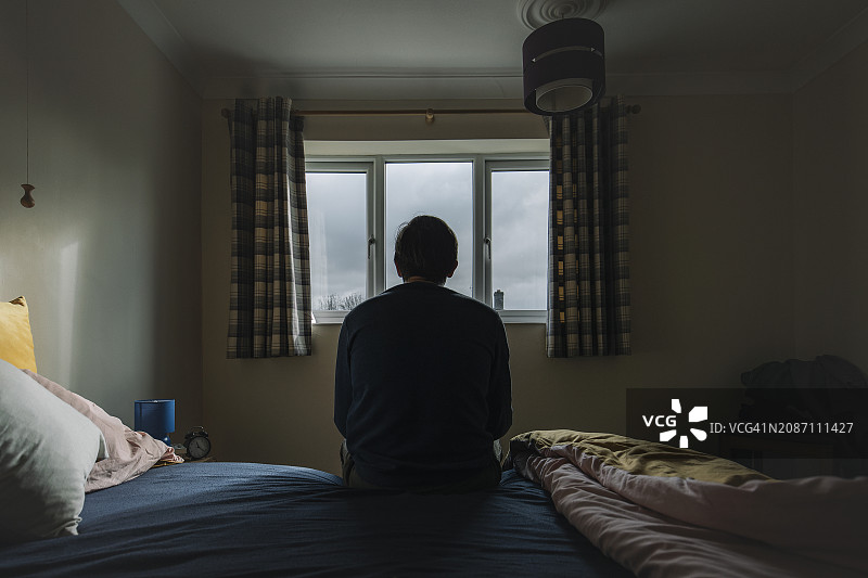 坐在床上情绪低落的成熟男人背影图片素材