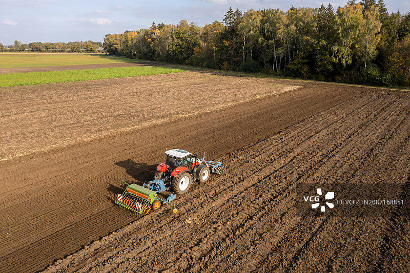 红色拖拉机在耕地上播种图片素材
