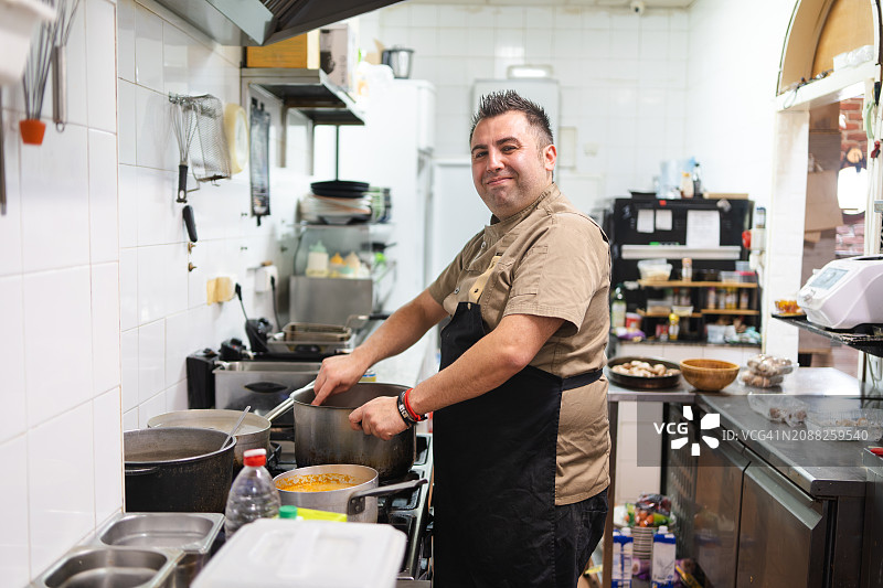 厨房里自豪的厨师和烹饪锅具图片素材