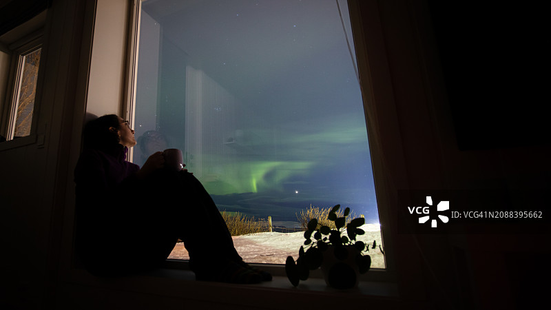 年轻女人在家观看北极光图片素材