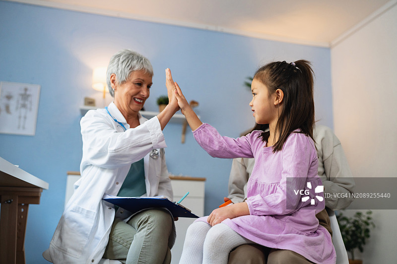 年度体检期间，儿科女医生与一名女孩击掌图片素材
