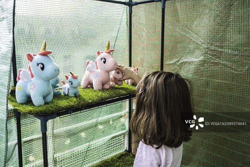 小女孩看着毛绒独角兽展示品图片素材