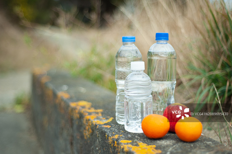 混凝土长凳上的塑料瓶装水和水果图片素材