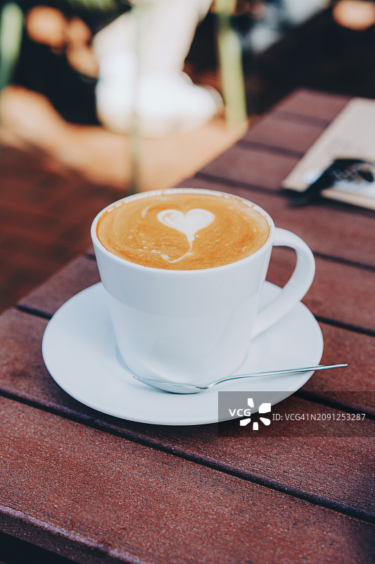 木桌上的拿铁艺术卡布奇诺咖啡图片素材