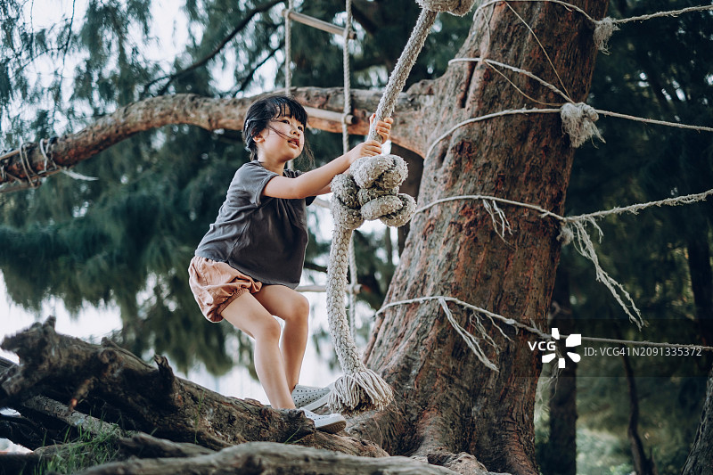 活泼的亚洲小女孩户外公园玩绳索秋千图片素材