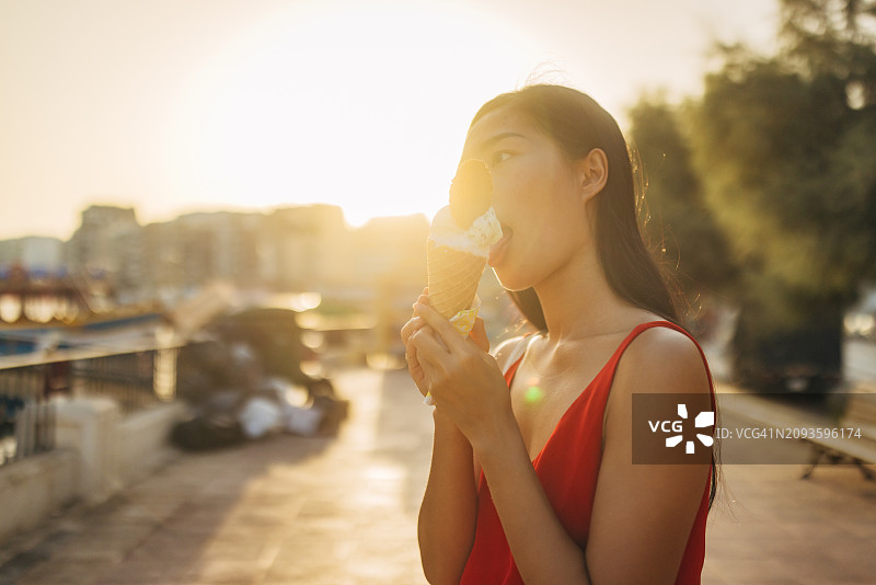 中国台湾女人穿着夏装在户外吃冰淇淋，享受阳光明媚的夏日和假期图片素材