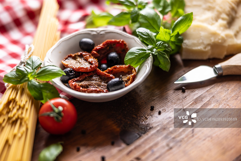 摆满意大利传统意面食材的复古木桌：意面、橄榄油、橄榄、番茄、罗勒、帕尔马干酪、大蒜、盐和胡椒图片素材