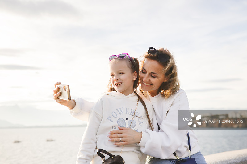 母女时光：中年母亲和女儿在土耳其安塔利亚分享拥抱、自拍和视频聊天图片素材