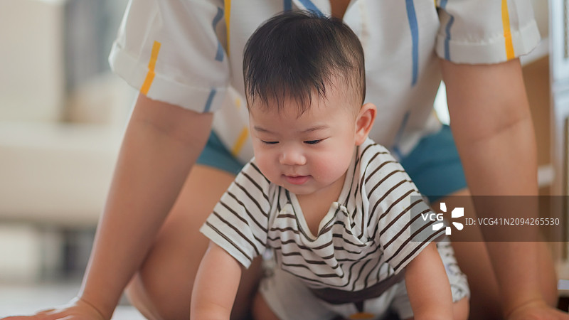 亚洲家庭温馨日常：宝宝学爬，妈妈在一旁鼓励支持图片素材