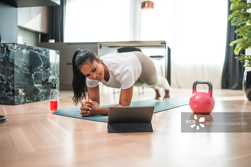 年轻女子使用平板电脑锻炼的室内照片图片素材