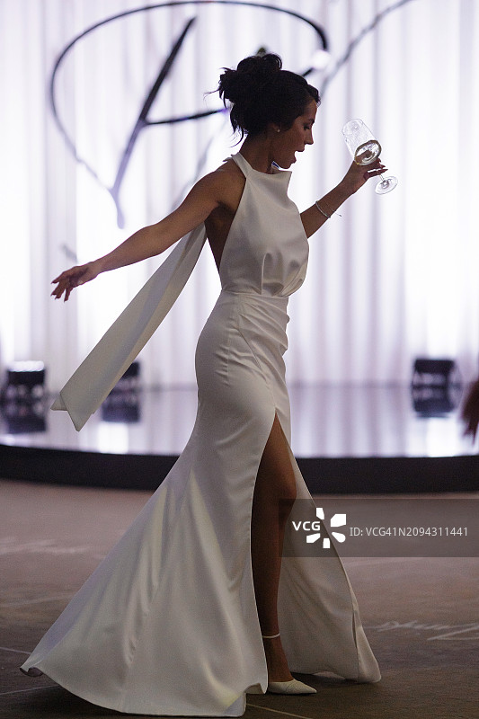 迷人的新娘在走廊里端着空杯跳舞图片素材