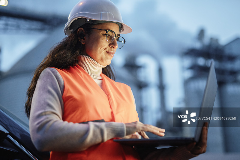 在石油和天然气行业工作到深夜，用笔记本电脑工作的专注女工程师图片素材
