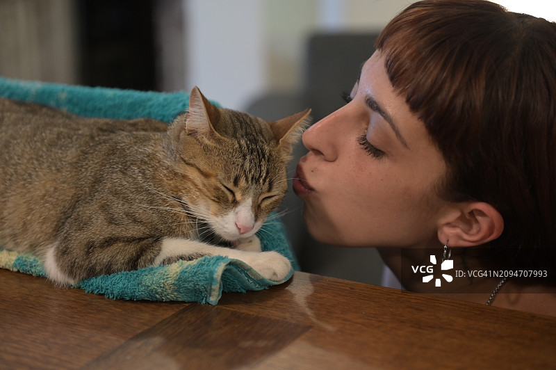 女人看着桌子上的猫图片素材
