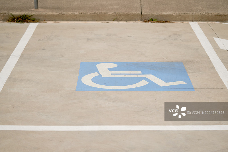 建筑物外停车场内的蓝色轮椅残疾人标志，侧视图，无人图片素材
