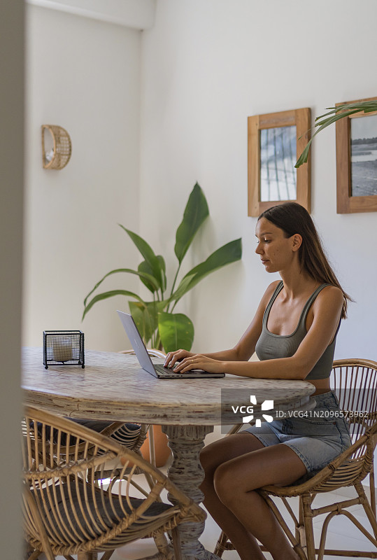 年轻女人在家远程工作。图片素材