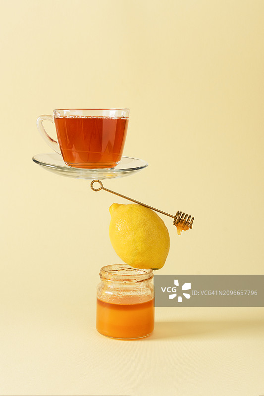 黄色背景下蜂蜜柠檬健康红茶的创意静物图片素材