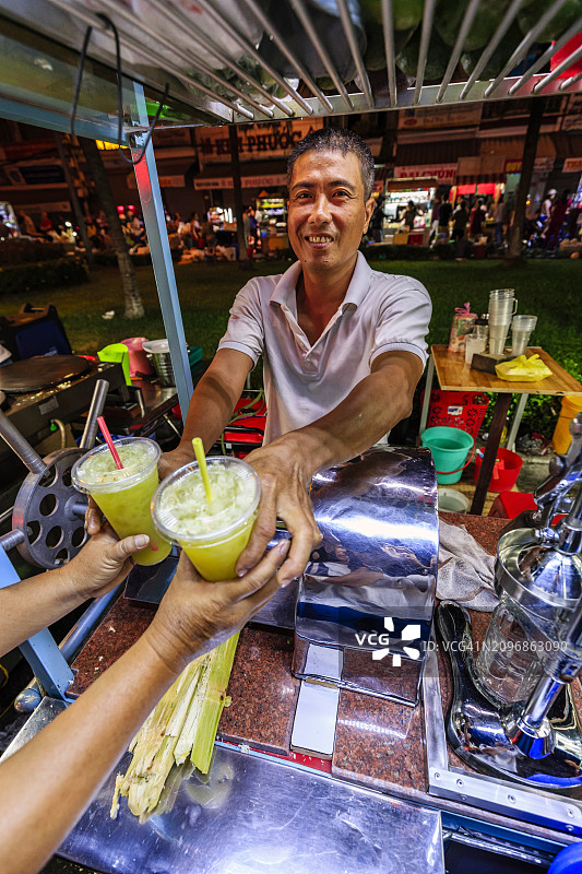 越南湄公河三角洲夜市上的甘蔗汁小贩图片素材