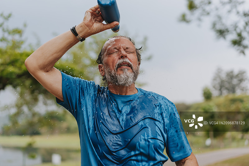 一位在运动后喝水的年长男人肖像图片素材