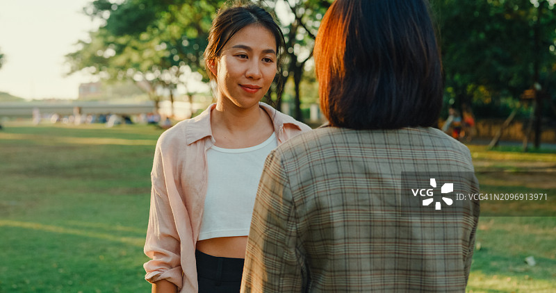 两名年轻亚裔女性在公园互相支持拥抱，关注心理健康，强调同情和关爱。户外心理健康社区支持。图片素材