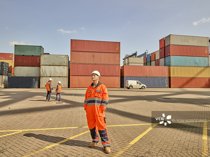 身穿反光工作服的码头工人和货运集装箱图片素材