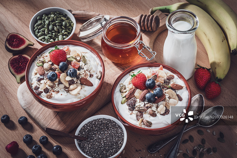 早餐桌上的两碗格兰诺拉麦片、水果和种子图片素材