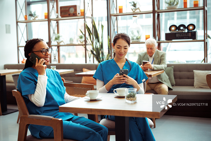 在自助餐厅休息时使用智能手机的医务人员图片素材