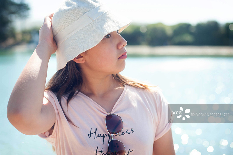 Z世代女孩在泻湖边戴着白色帽子沉思图片素材