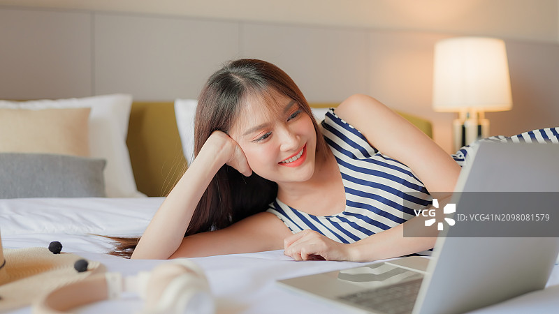 亚洲居家隔离女性在卧室床上用平板电脑观看在线电影图片素材