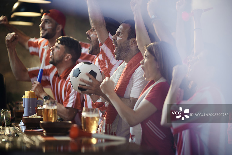 在酒吧里庆祝他们最喜欢的球队进球的快乐足球迷图片素材