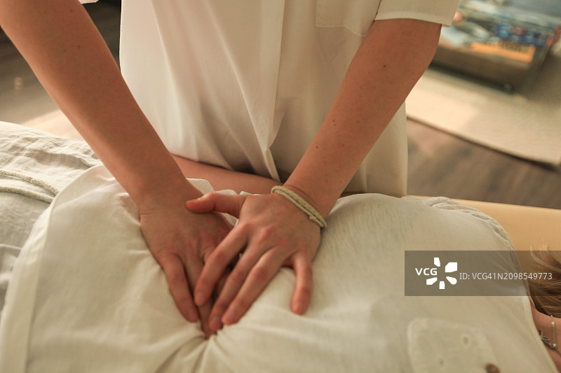 女士的双手为女孩做腹部按摩图片素材