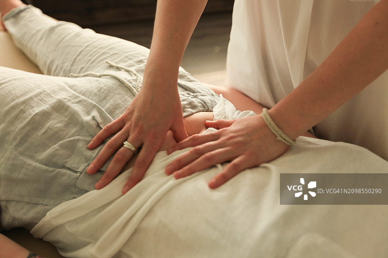 女士的双手为女孩做腹部按摩图片素材