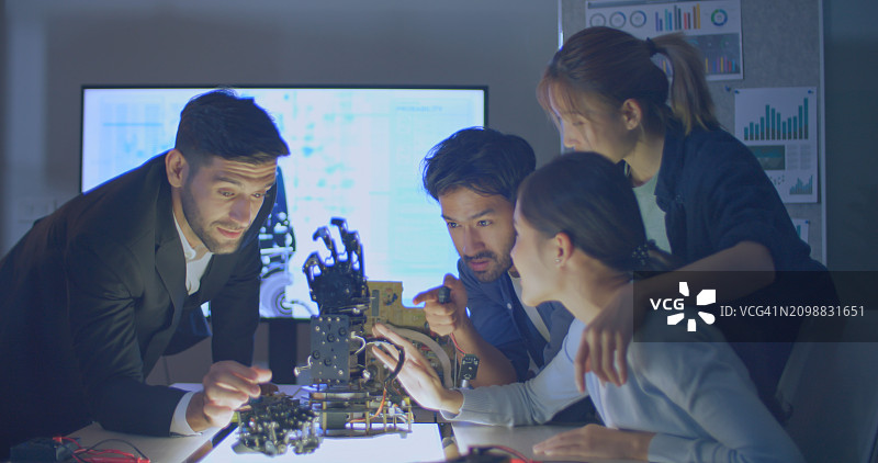 办公室里，一个由不同国籍的人组成的团队享受着现代手部机器人学习计划图片素材