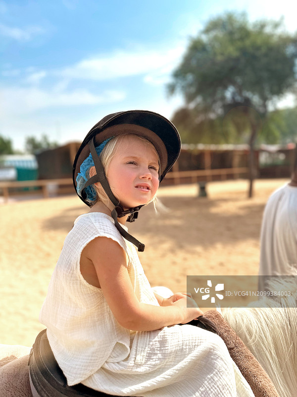 快乐可爱的小金发女婴在公园里骑马图片素材