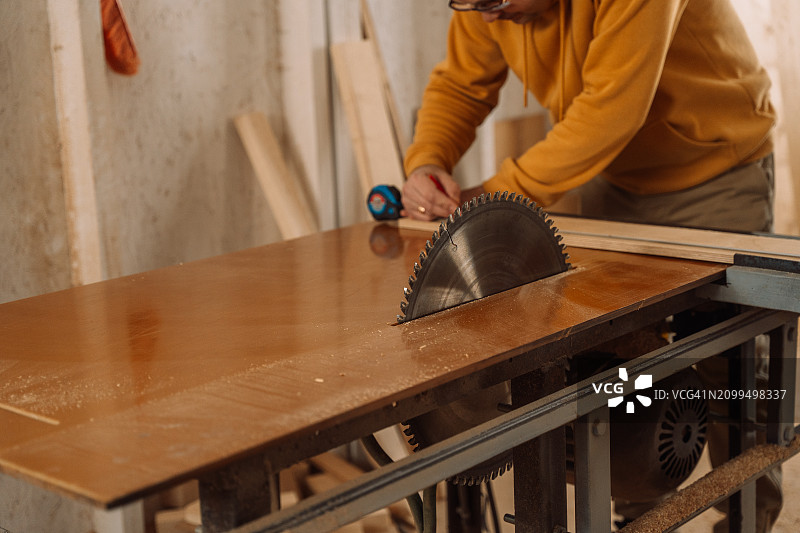 男人将木制品锯成圆形图片素材
