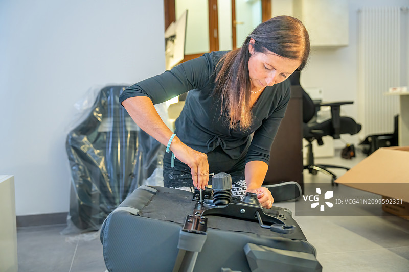 女人在家组装新家具，购买新物件，爱好理念。白人女性安装游戏椅图片素材