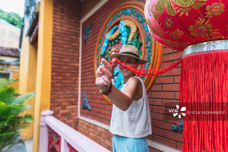 面带微笑的年轻女人在会安寺庙触摸灯笼图片素材
