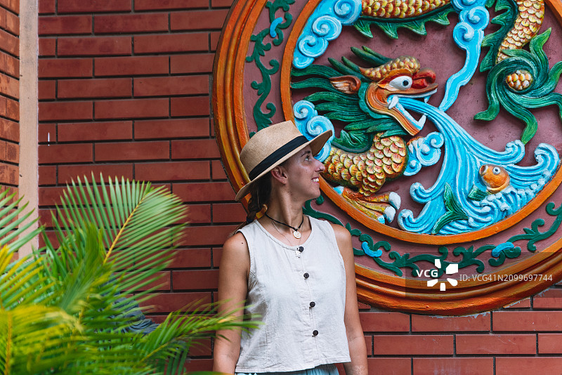 女士在会安寺庙墙壁前欣赏中国画图片素材