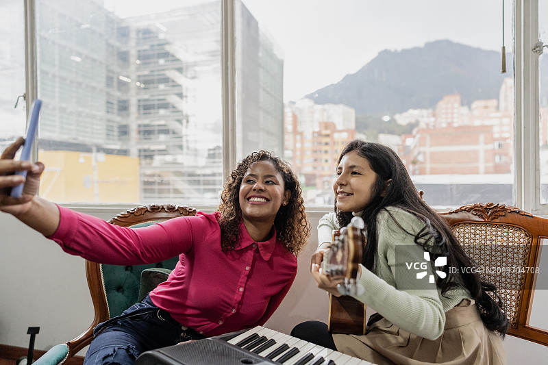 与在家弹吉他的女儿自拍的女人肖像图片素材