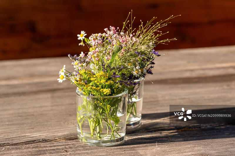 奥地利萨尔茨卡默古特户外乡村木桌上的两杯彩色野花图片素材