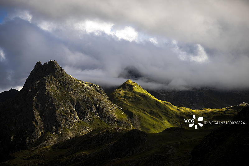 奥地利欧洲，恰格斯山区，雷蒂孔山，蒙塔丰山脉的草山，光线柔和，乌云压境图片素材