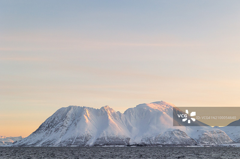 挪威日出时分高耸的雪山图片素材