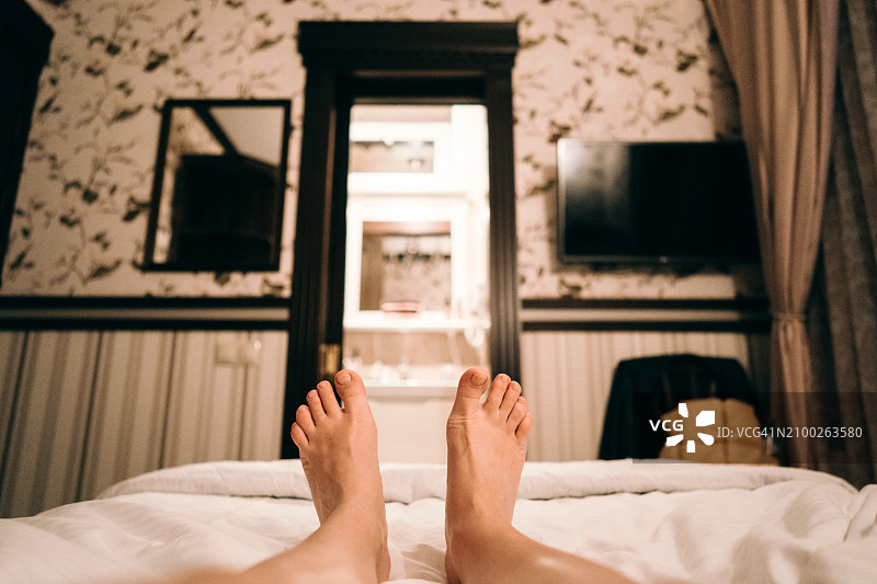 酒店单人小黑屋里，浴室旁的床上的女人。独自出差或度假，享受宁静的休息图片素材