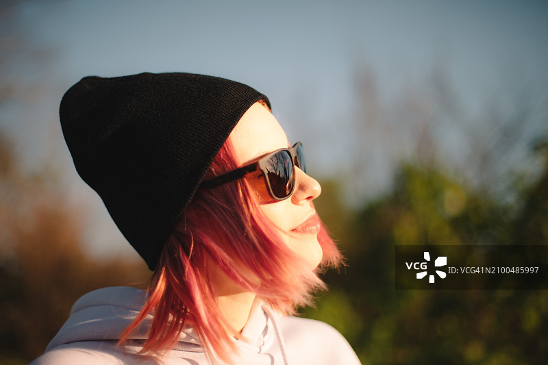 年轻女子坐在户外，目光移开的肖像图片素材