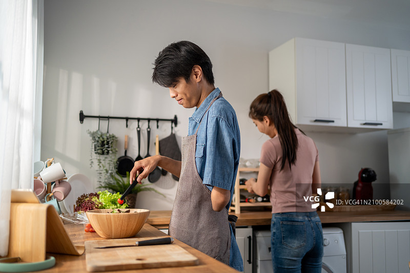 亚洲年轻残疾男子与家人在厨房烹饪美食图片素材